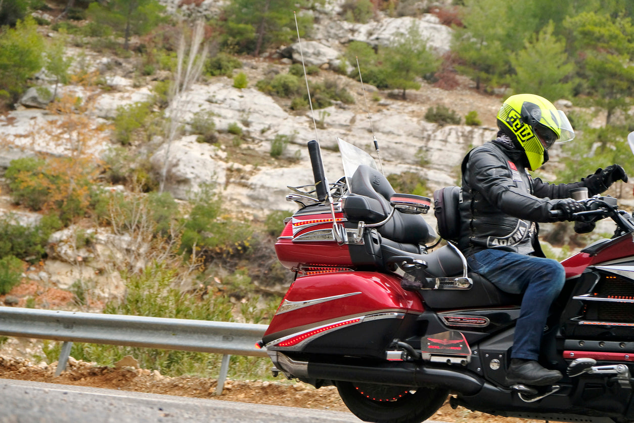 man riding a red motorcycle down a mountain