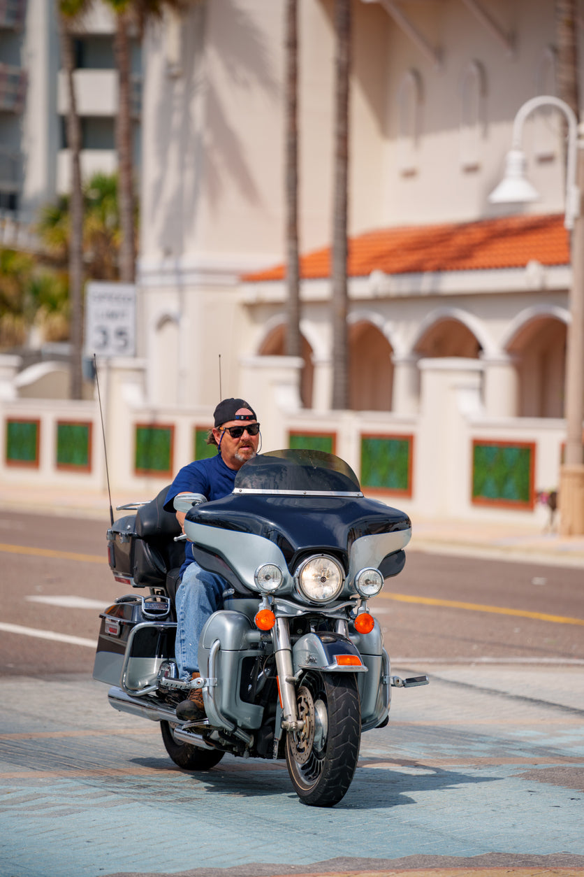 man riding a black bagger motorcycle down the street